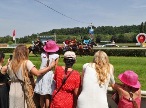 Saarbrücken lädt zum späten Saisonauftakt und Feiertags-Renntag Rennbahnbesucher betrachten die Pferde und Jockeys im Rennen beim Sparkassen-Renntag